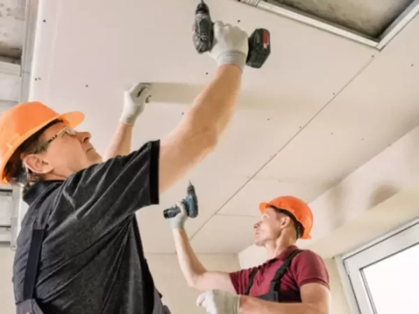 os_trabalhadores_estao_usando_parafusos_e_uma_chave_de_fenda_para_fixar_placa_de_gesso_no_teto_1.jpg.webp
